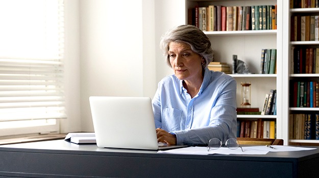 woman in front of bookcase using computer