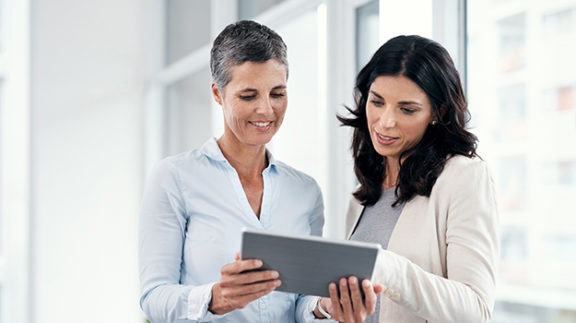 two workers looking at tablet in office setting