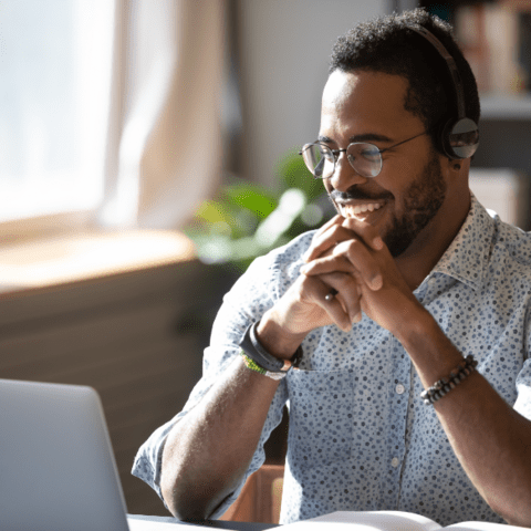 Man with headphones on looking at a laptop and smiling