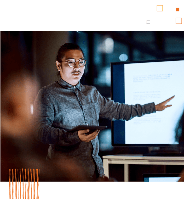 Man presenting in front of screen in dark room