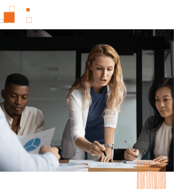 Woman writing on documents on table with coworkers