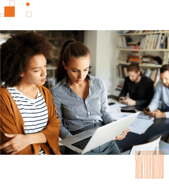 Women on laptop with coworkers at table in background