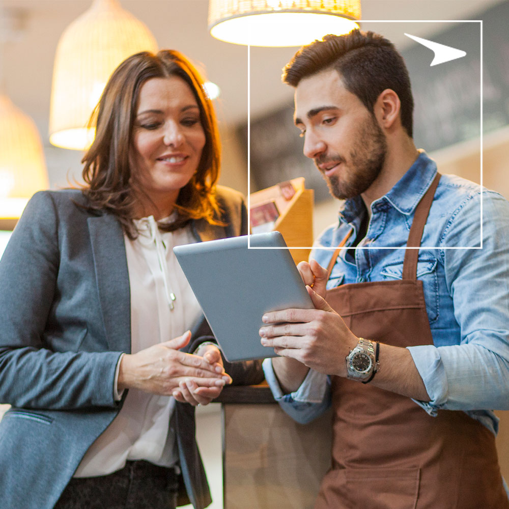Woman in suit and man in apron looking at tablet in restaurant