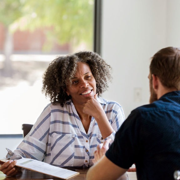 Woman sitting at desk interviewing job candidate with clipboard