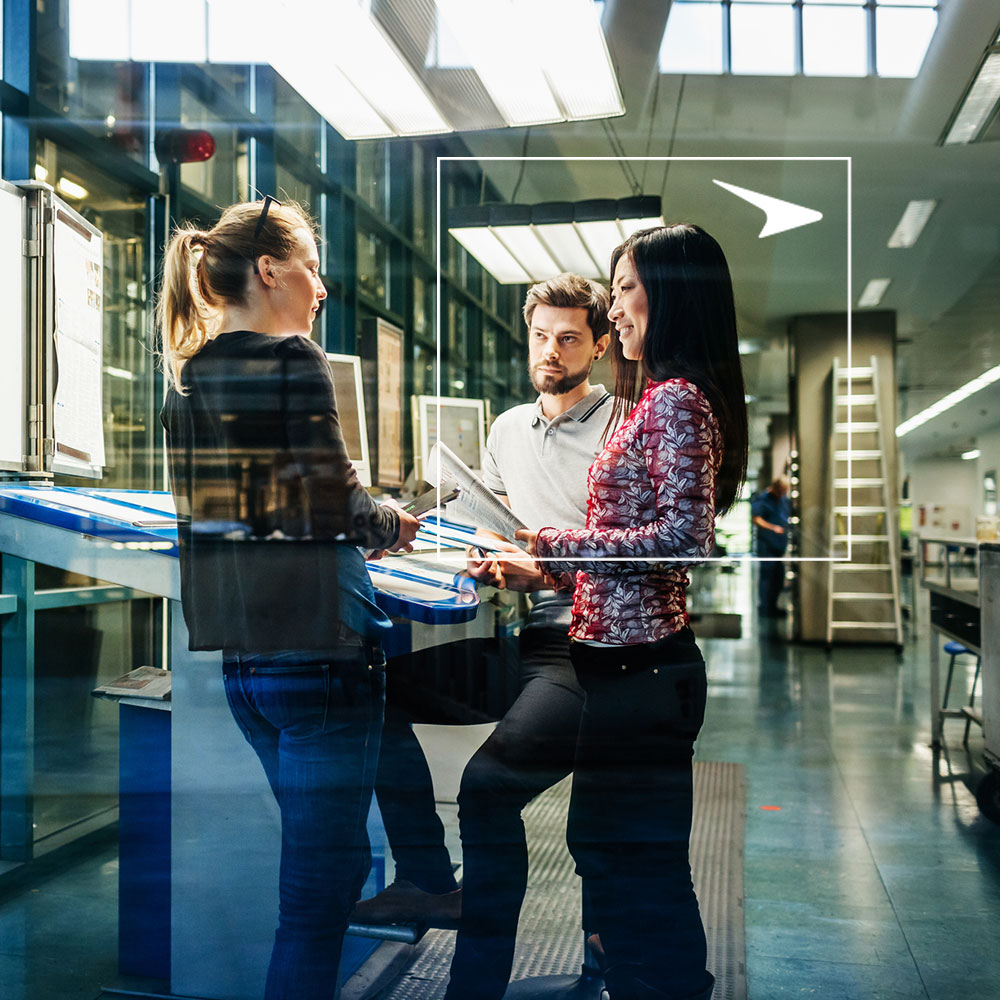 Three coworkers talking against industrial background