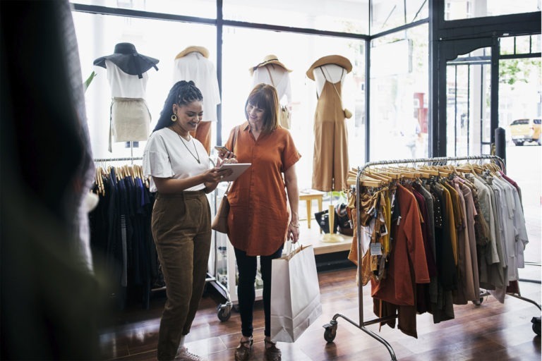 Woman checking customer out on tablet in clothing store