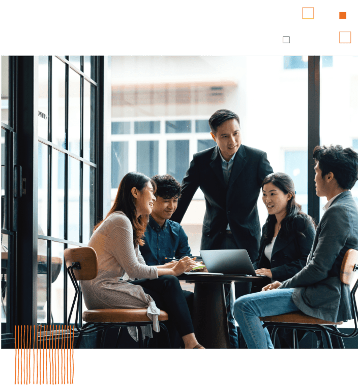 Group of coworkers with laptops talking at round table