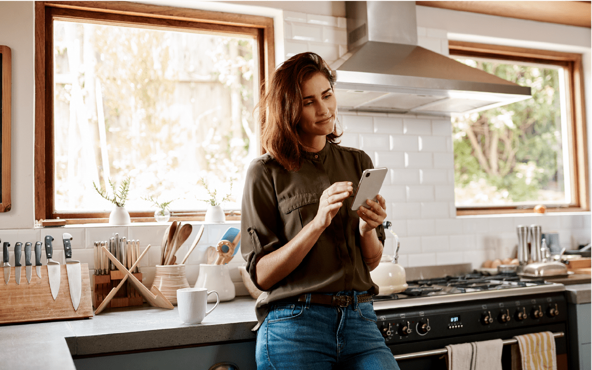 Woman looking at cell phone in kitchen