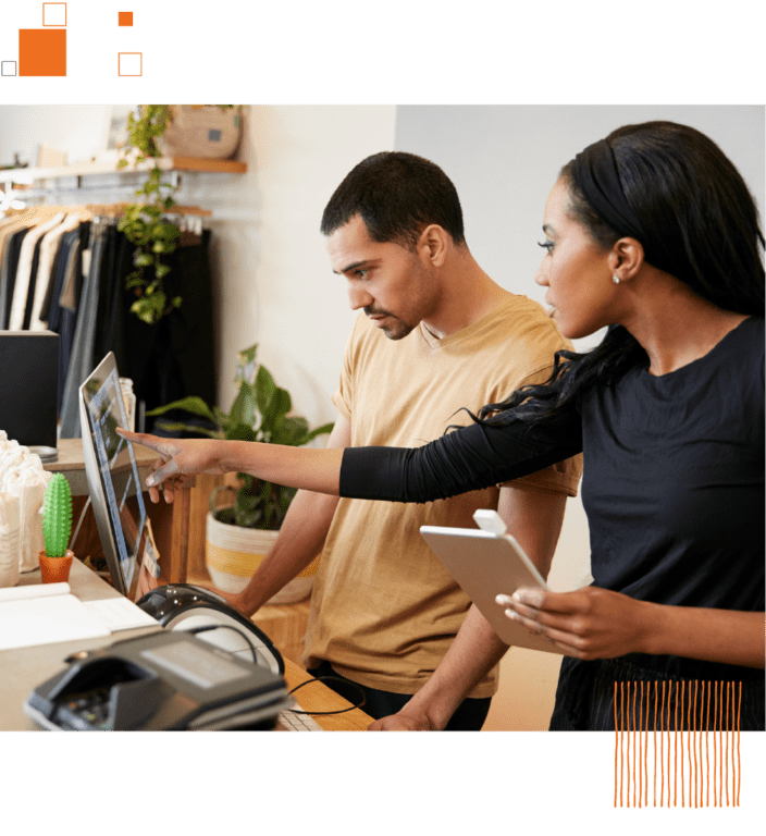 Man and woman looking at computer against clothing store background