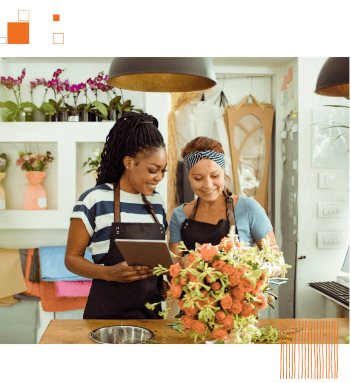 Two women in aprons making floral arrangement in flower shop