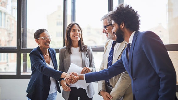 Man shaking hands with with group of people during job interview