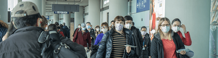 travelers in airport wearing masks to prevent coronavirus