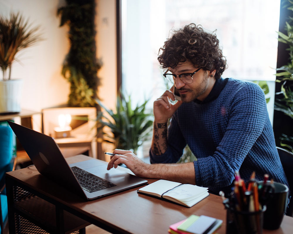 Man on phone and working on laptop