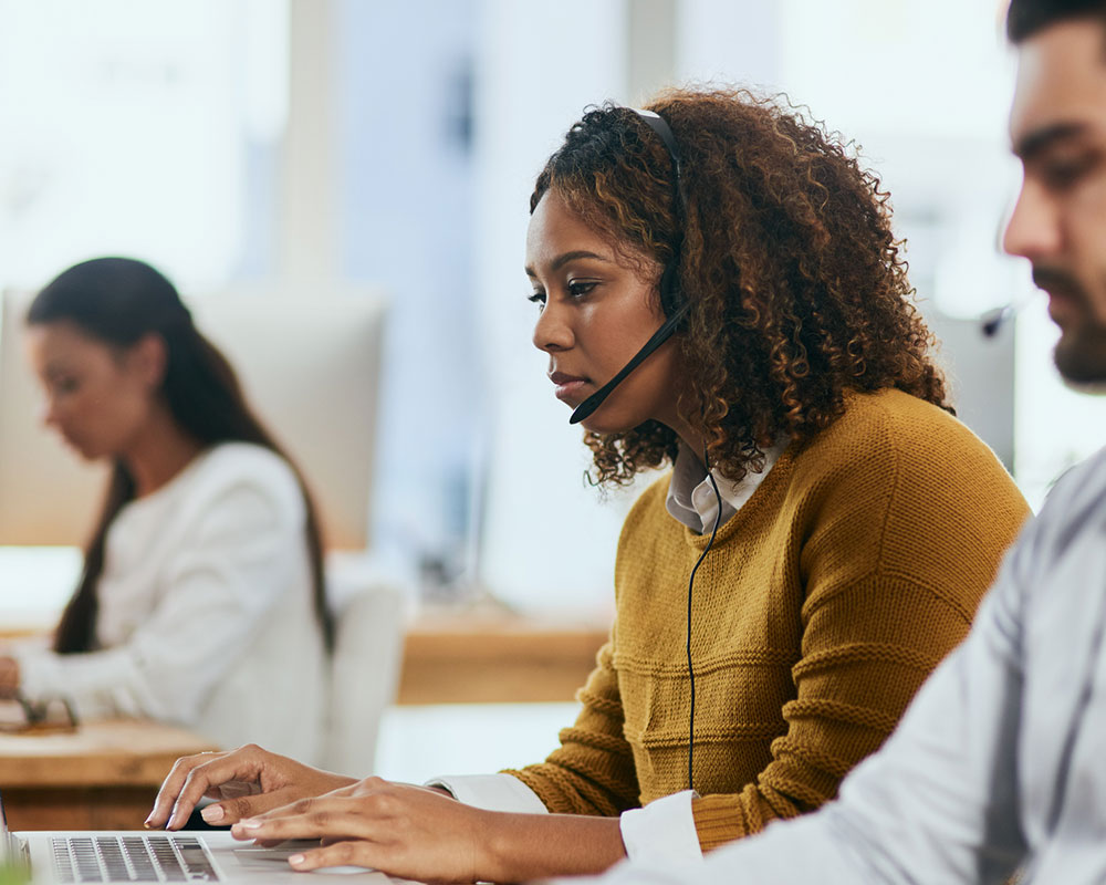 Woman with phone headset working on laptop