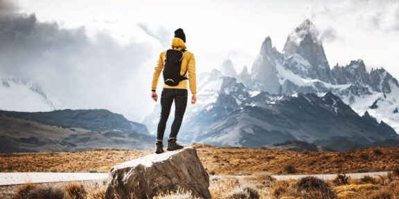 Man standing on a boulder in a mountainous terrain