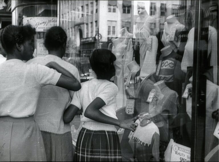Three girls looking into shop window with black-and-white effect