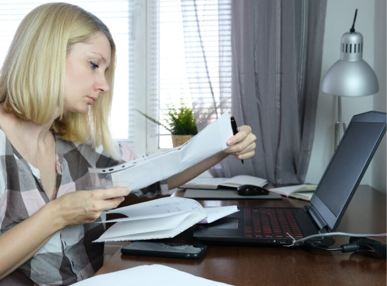 Woman working at home with documents and laptop