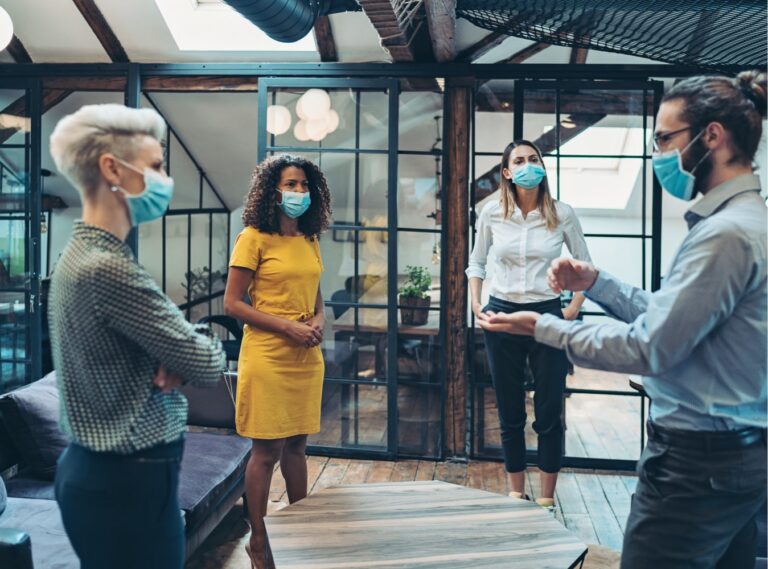 Group of coworkers wearing face masks and talking in office