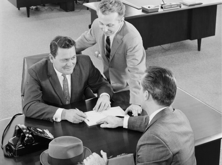 Three men working at desk with black and white effect