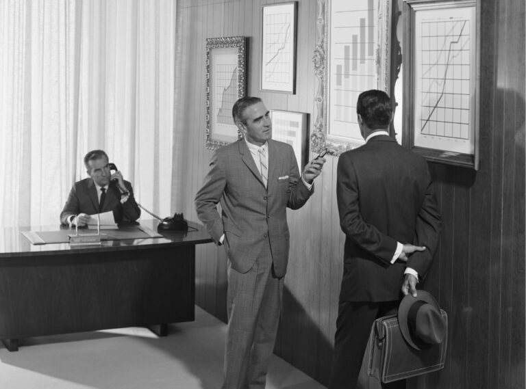 Three men in office looking at bar graphs with black and white effect