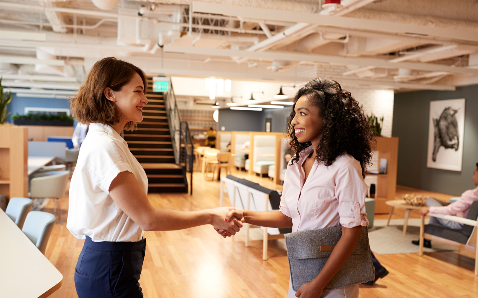 Two coworkers shaking hands in bright office