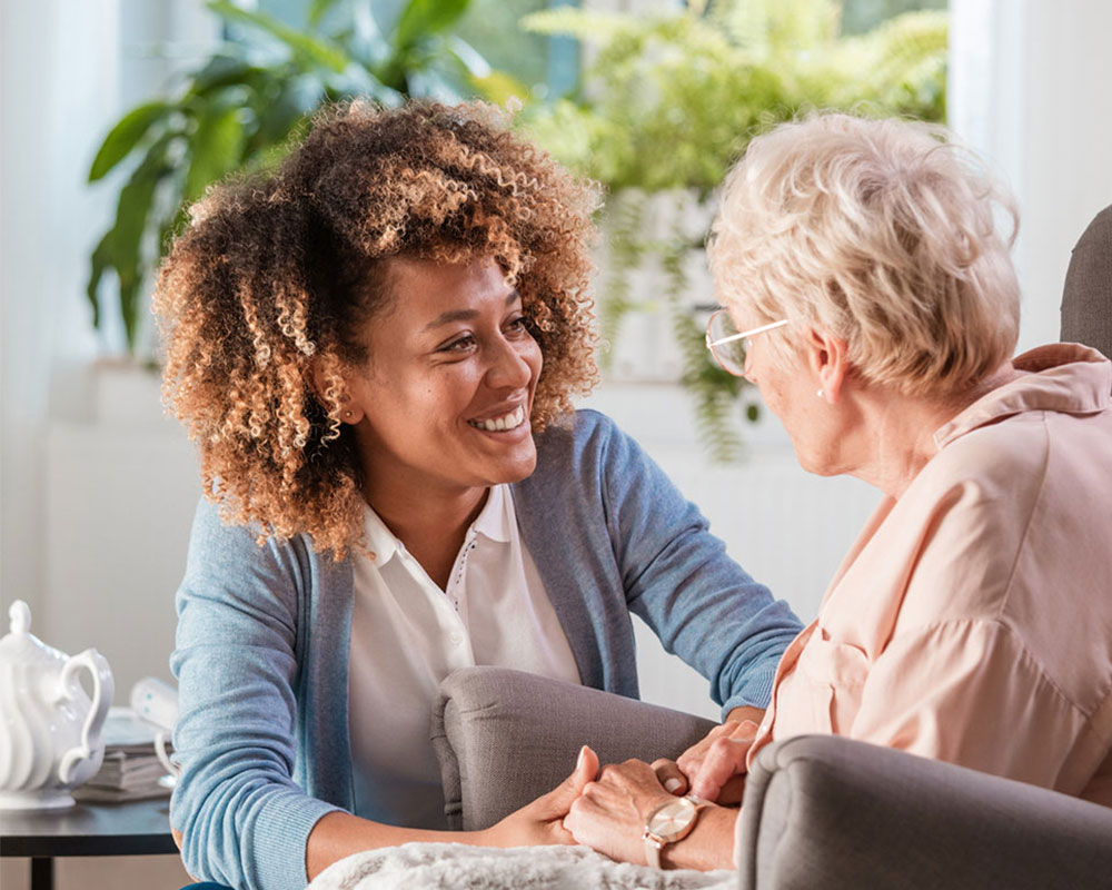 Woman helping older woman in chair