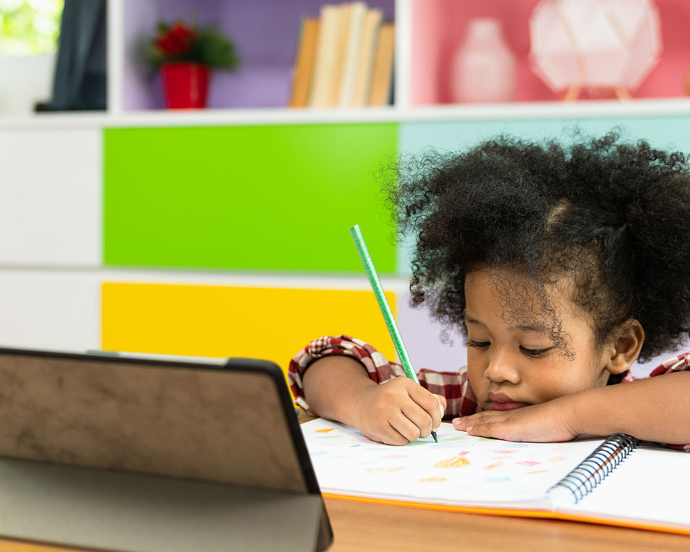 Little girl at desk drawing in coloring book