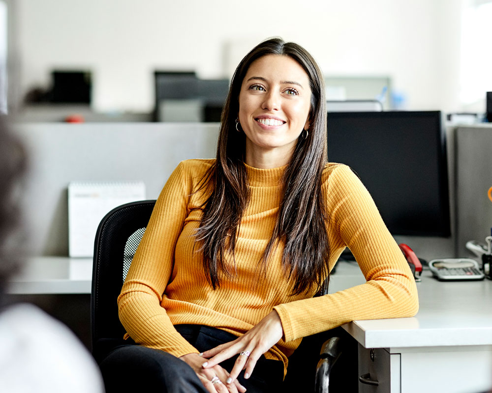 Woman sitting in cubicle smiling