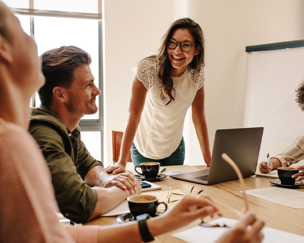 Woman at coffee shop table smiling at coworkers