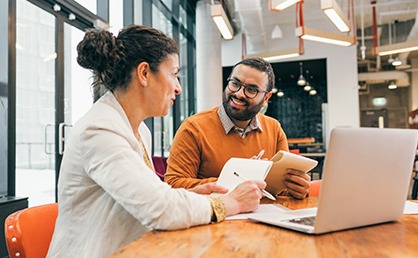 Professional woman and man sitting at a table with a laptop