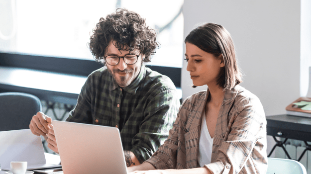 male and female professionals sitting side by side looking at a laptop