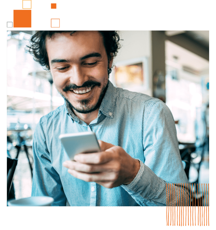 man in button down smiling at his phone.