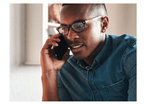 man with glasses and denim shirt on his cell phone