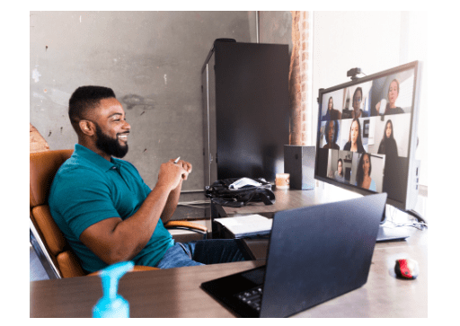 man in a teal shirt sitting at a home office smiling at a screen with a conference call