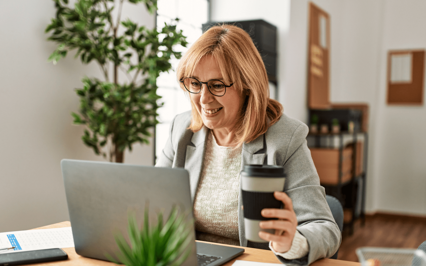 woman with coffee cup reading computer screen