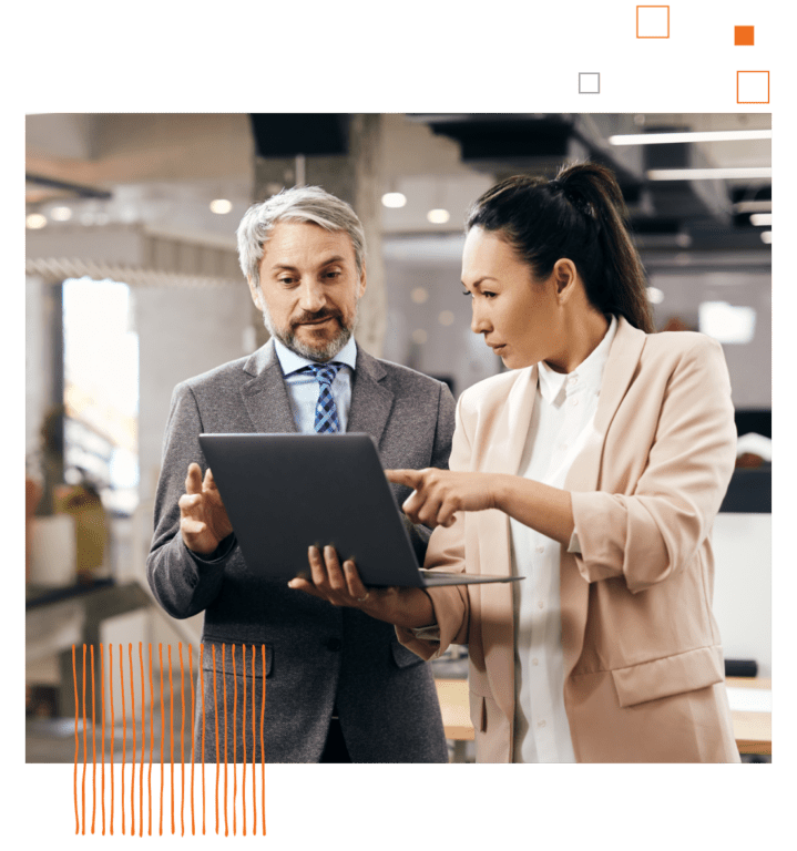 woman and man standing and looking at laptop