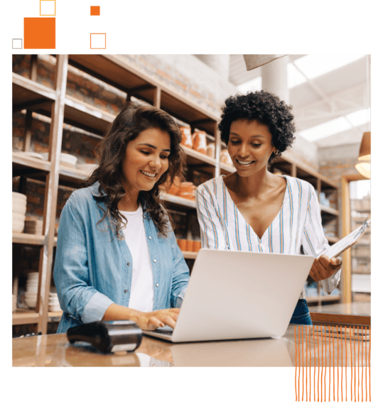 two women standing around a laptop smiling