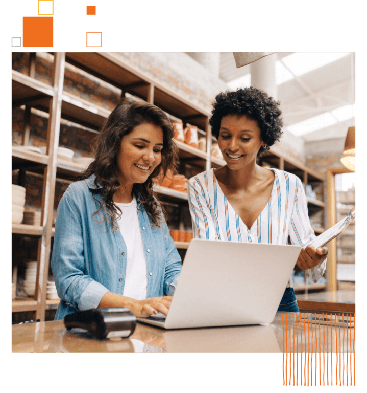 two women standing around a laptop smiling