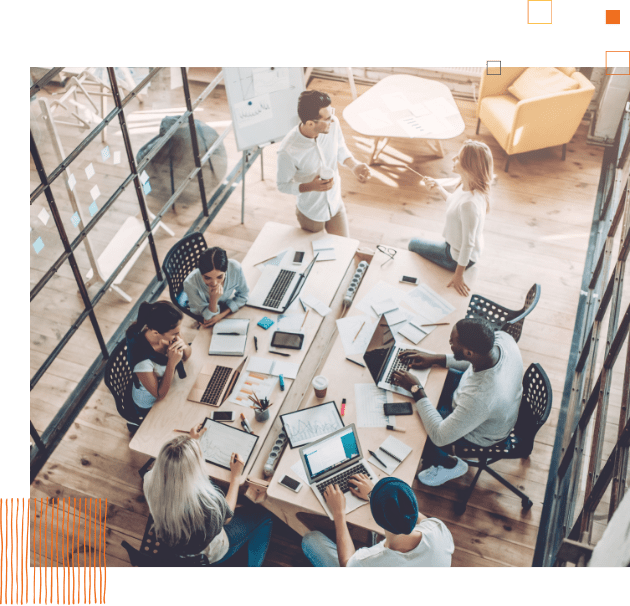 overhead of workers sitting at a table working on computers 