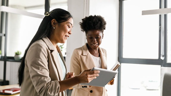 two women working side by side on a tablet