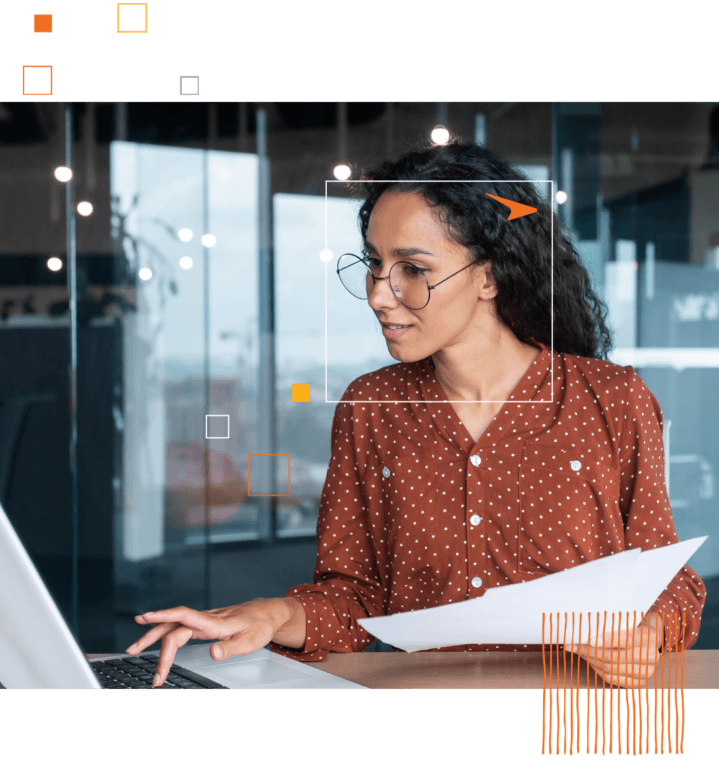 woman in glass with polka shirt typing on laptop