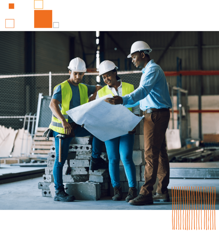 three workers at a construction site looking at blueprints