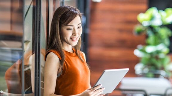 smiling woman looking at a tablet in her hand