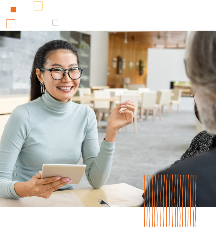 smiling woman looking across table at another person