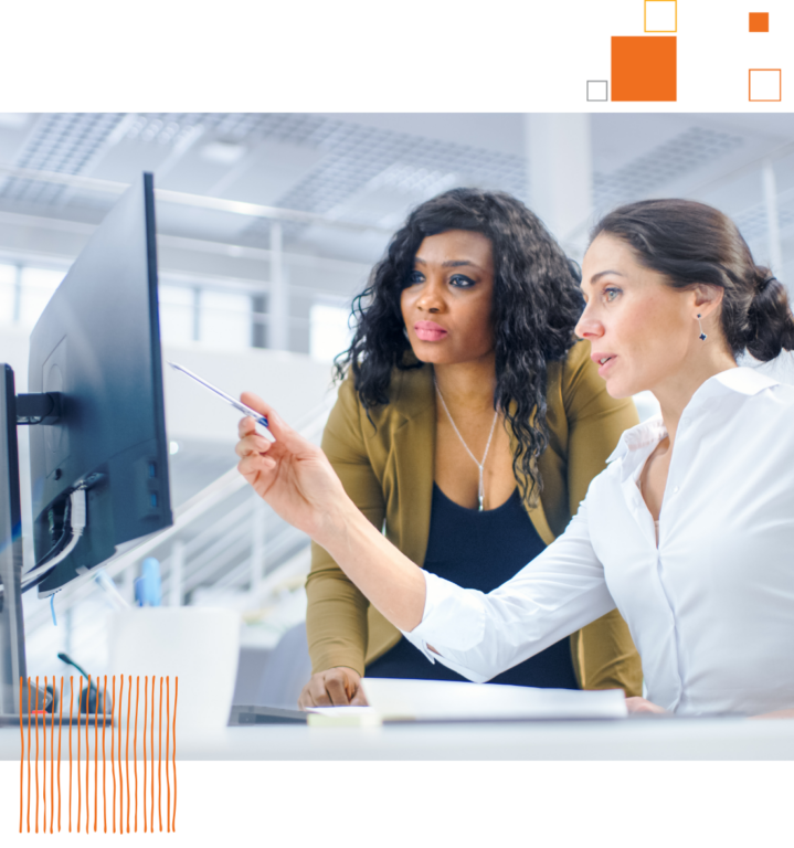 woman pointing at computer with another woman standing beside her