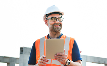 male worker holding notepad wearing hardhat and vest