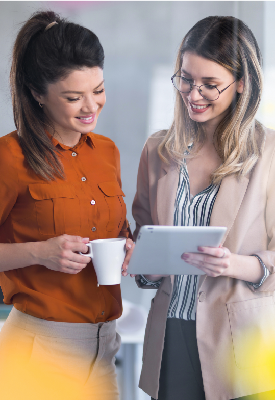 two smiling women looking at tablet