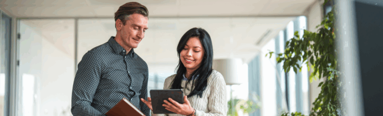 two employees analyzing a payroll reports on a tablet