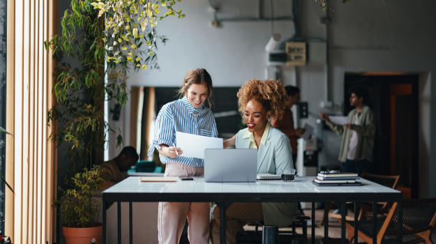 two employees looking at people analytics data on their computers.