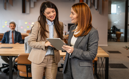 two employees smiling and looking at a tablet